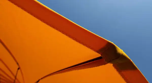 Orange Sonnenschirm-Stoff mit Baumwolle für UV-Schutz vor blauem Himmel.