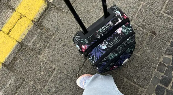 Podróżujesz z Ryanair? Jaki bagaż w cenie biletu? Mała, kwiecista walizka na kółkach czeka na lot.