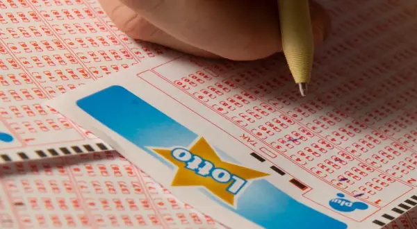 Dłoń zaznacza liczby na kuponie Lotto. Czy to będą zwycięskie lotto kaskada wyniki?