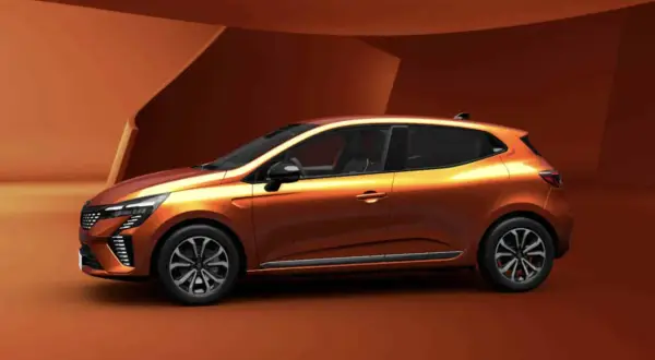Pomarańczowy Renault Clio 6 z nowoczesnym designem, prezentowany na tle architektonicznych form w odcieniach brązu.