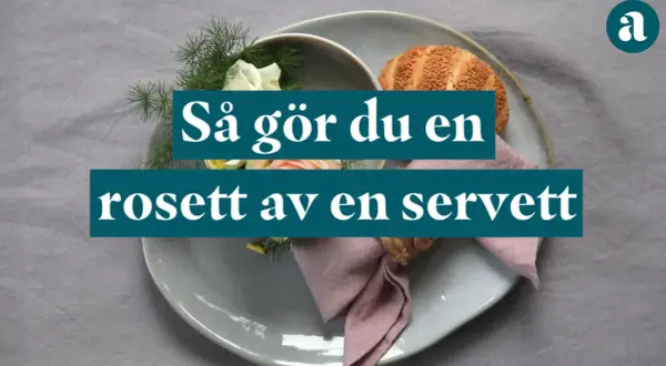 En dukning med en rosett av en servett, blommor och en bulle.