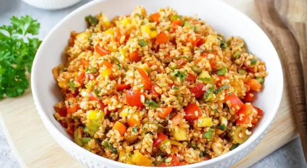 Frischer bulgur salat mit bunten Paprikawürfeln und Kräutern, serviert in einer weißen Schüssel.