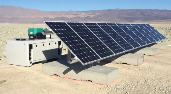 Un impianto fotovoltaico ad isola in un paesaggio arido, con pannelli solari e un'unità di controllo. Le autorizzazioni per questo sistema sono fondamentali per l'energia sostenibile.
