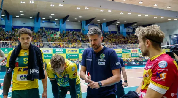 Trener Ireneusz Mazur udziela wskazówek siatkarzom w hali sportowej, wśród kibiców.