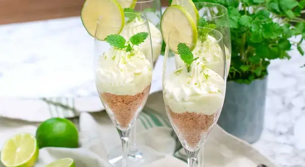 Söta key lime pie i glas, toppad med vispgrädde och lime. En perfekt dessert för sommaren.