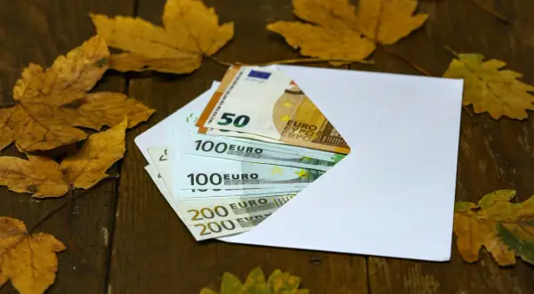 Koperta z euro na chrzciny, wśród jesiennych liści. Ile daje się na chrzciny? Pieniądze na prezent.