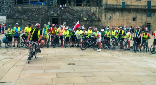 Grupa rowerzystów w kamizelkach odblaskowych przed katedrą. Szukasz najlepszych tras pielgrzymkowych w Polsce dla rowerzystów?