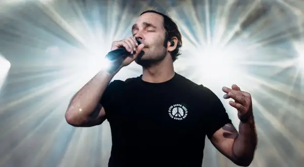 Sänger mit geschlossenen Augen und Mikrofon, der seinen erfolgreichsten Song aller Zeiten performt.