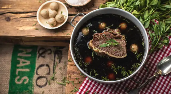 Ein köstliches Tafelspitz-Rezept: Zartes Rindfleisch in dunkler Brühe mit kleinen Klößchen und frischer Petersilie.
