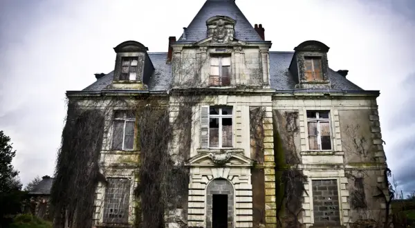 Vaste manoir urbex envahi par la végétation, fenêtres brisées et portes barricadées. Un lieu figé dans le temps, invitant à l'exploration.