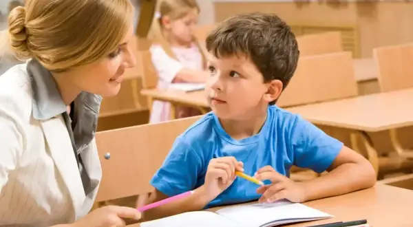 Nauczycielka wspiera chłopca w nauce, pokazując mu, jak rysować. To przykład indywidualnego podejścia w kształceniu specjalnym.