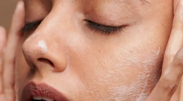 Une femme applique une crème sur son visage. C'est le moment idéal pour savoir quand appliquer crème solaire visage pour une protection optimale.