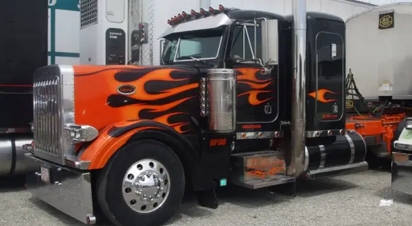 Camion tuning noir et orange avec des flammes, prêt pour la nuit.