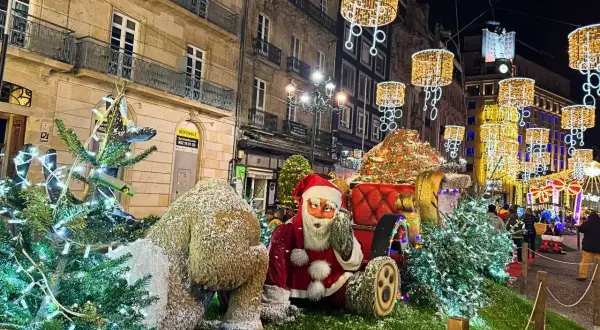 Papá Noel y un reno cubierto de nieve junto a árboles de Navidad adornados con luces. Las calles de Vigo brillan con la magia de la Navidad.