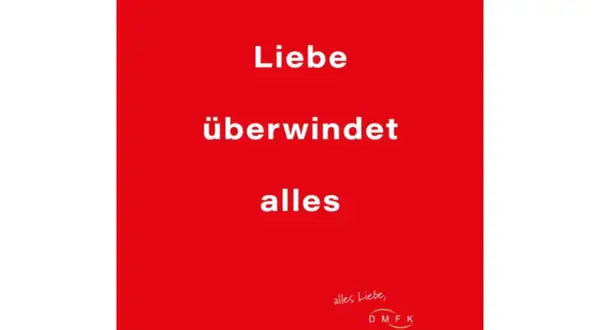 Rode achtergrond met witte tekst: "Liebe überwindet alles". Een boodschap dat liefde overwint alles, met een kleine handgeschreven tekst en logo rechtsonder.