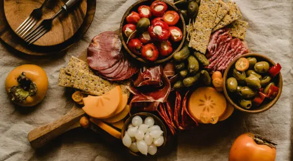 Deska serów i wędlin z owocami kaki, oliwkami i piklami. Idealna na wino aperitif.