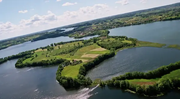 Malowniczy kółko raduńskie z lotu ptaka, otoczone jeziorami i zielonymi polami.