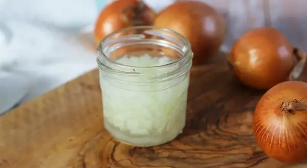 Zwiebelsaft husten: Gehackte Zwiebeln in einem Glas, bereit zur Zubereitung eines natürlichen Heilmittels gegen Husten.
