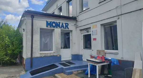 Budynek Monaru z niebieskim napisem, wejściem i otoczeniem.