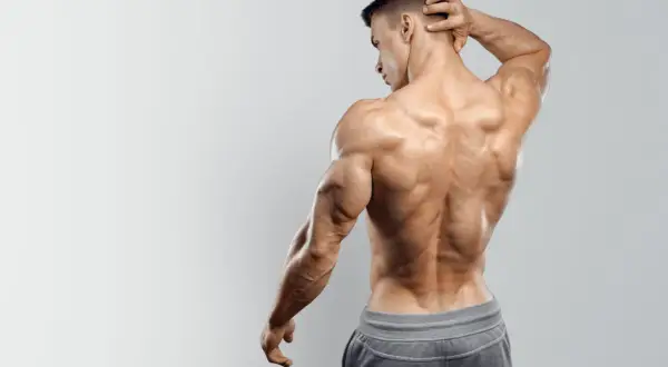 Uomo con muscoli spalle e schiena scolpiti, posa di profilo con mano dietro la nuca.