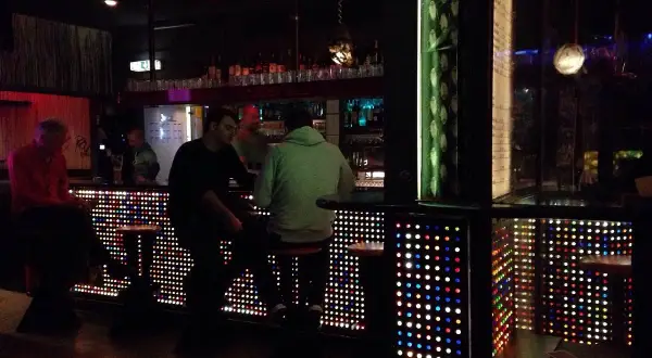 Leute sitzen an einer Bar in Stuttgart, die mit bunten Lichtern beleuchtet ist. Ein gemütlicher Abend im Oblomow.