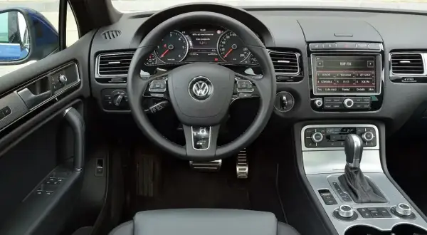 Wnętrze Touarega 3.0 TDI: kierownica, deska rozdzielcza z radiem i panelem klimatyzacji, dźwignia zmiany biegów.