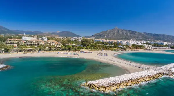 Piękne plaże i turkusowe morze w Puerto Banús, z górami w tle.