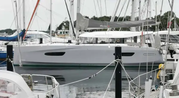 Eine moderne Segelyacht, die Excess 14, liegt im Hafen. Ihr elegantes Design und die großen Fenster versprechen Komfort.