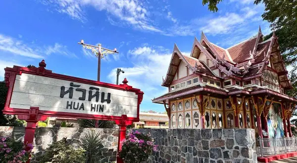Znak "Hua Hin" przed zabytkowym budynkiem dworca kolejowego w Tajlandii.