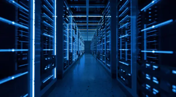 Wnętrze nowoczesnego data center z rzędami serwerów oświetlonych niebieskim światłem.