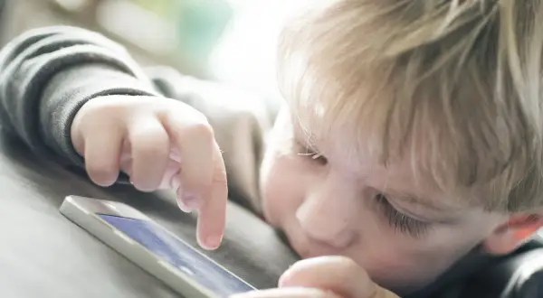 Un enfant blond joue sur un téléphone. Est-ce le wifi ou la 4G le plus dangereux pour lui ?