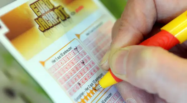 Prawda o rzekomych wróżbitach, którzy trafili liczby w Eurojackpot. Dłoń zaznacza liczby na kuponie lotto.