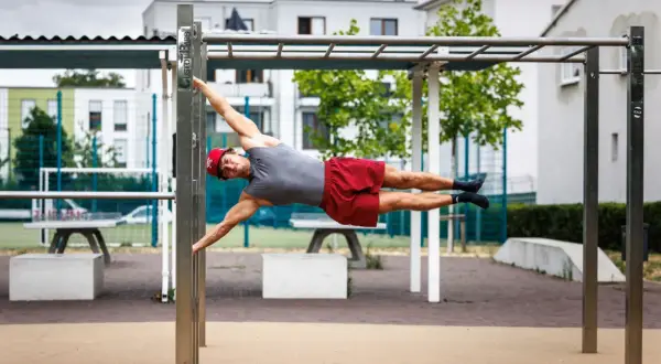 Mann hält die Flagge auf einem Calisthenics-Park. Das zeigt, was ist Calisthenics: Kraft, Balance und Körperbeherrschung.