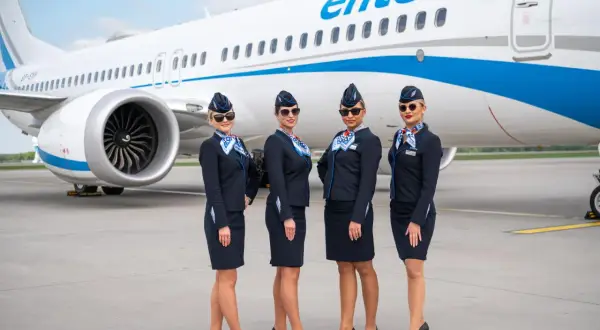Cztery stewardessy Enter Air w granatowych mundurkach pozują przed samolotem. Czekają, by serwować pyszne jedzenie w przestworzach.