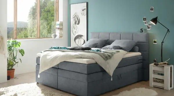 Ein Schlafzimmer mit einem Boxspringbett in Grau und einer Wand in Türkis. Tolle wandfarben ideen für ein maritimes Flair.
