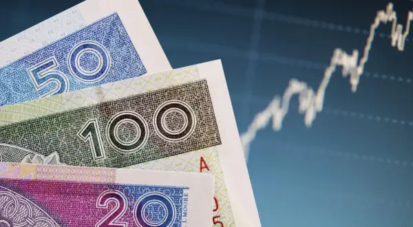 Polskie banknoty 20, 50 i 100 zł na tle wykresu giełdowego. Czy pieniądze w banku są bezpieczne?