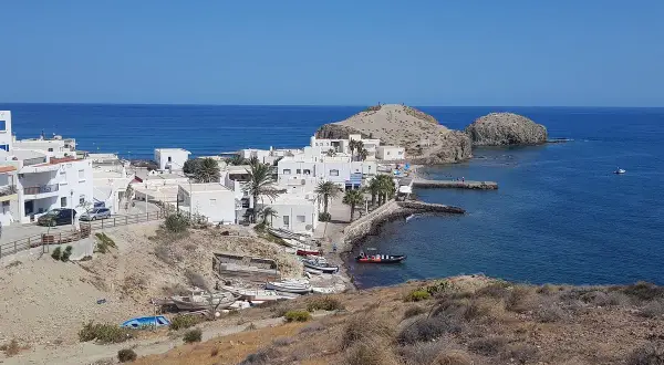 Vista panorámica de la **isleta del Moro, Almería**, con casas blancas, barcas y el mar azul.