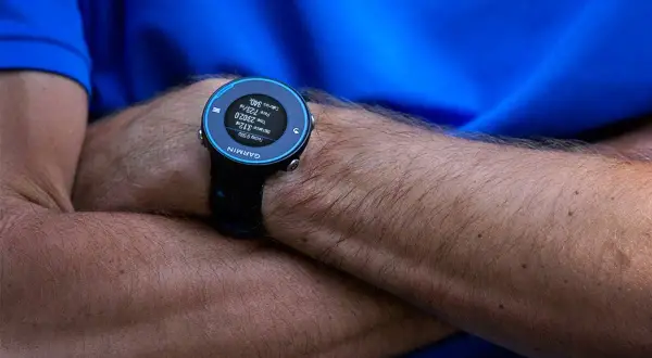 Montre Garmin Forerunner 620 au poignet d'un coureur, affichant distance, temps et calories.