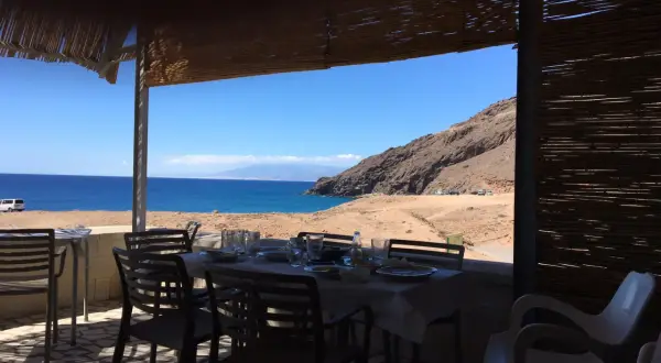 Mesas puestas en restaurantes en La Fabriquilla, Cabo de Gata, con vistas al mar y a la montaña.