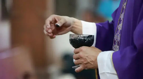 Dłoń księdza w purpurowej szacie trzyma kielich z winem. Dziś, 15 lutego, trwa ważna ceremonia.