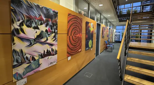 Moderne Kunstwerke schmücken die Wand einer Galerie in Bergisch Gladbach. Eine Treppe führt nach oben.