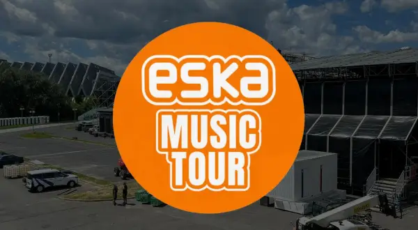 Pomarańczowe koło z napisem "ESKA MUSIC TOUR" na tle sceny koncertowej i parkingu.