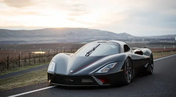 Czarny hypercar SSC Tuatara na drodze z widokiem na wzgórza o zachodzie słońca.