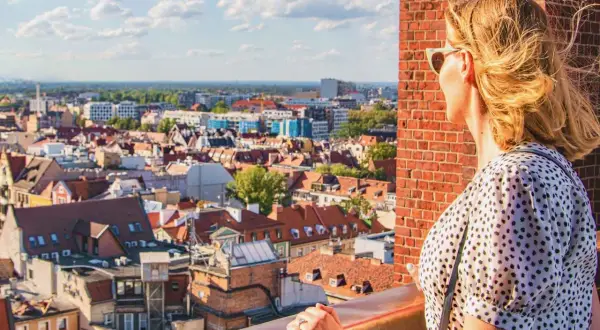 Kobieta podziwia panoramę Wrocławia, planując, co zobaczyć w 1 dzień. Widok na dachy kamienic i niebo.