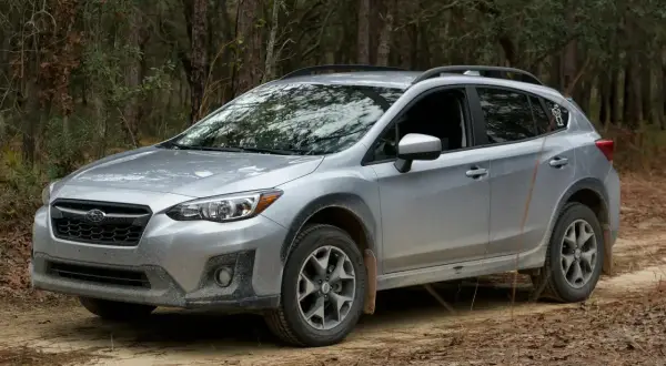 Srebrny Subaru Crosstrek na leśnej drodze, gotowy na przygodę.