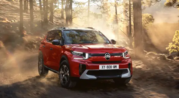 Röd Citroën C3 Aircross testkörs på en dammig skogsväg i solnedgången.