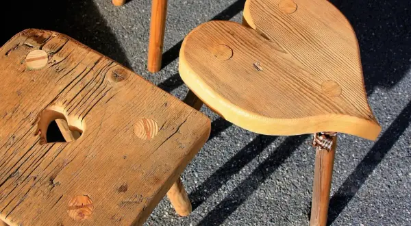 Drewniane taborety do kuchni, jeden w kształcie serca, drugi kwadratowy z wycięciem w kształcie serca.