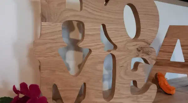 Grosse lettre en bois formant le mot "HOME", décorée de fleurs et d'une petite décoration orange.