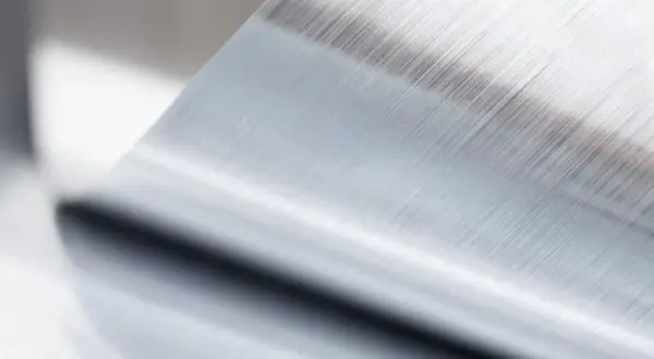 Szczotkowana powierzchnia metalu po procesie anodowania, z widocznymi równoległymi liniami.