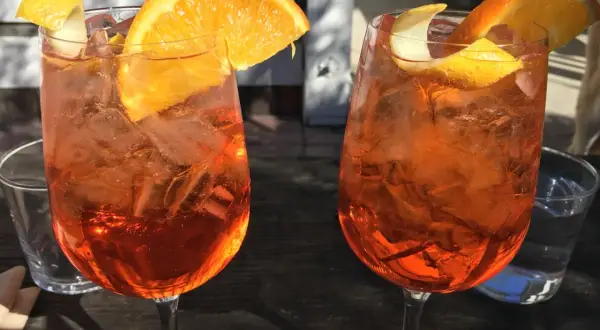 Dwa orzeźwiające aperitif z pomarańczą i skórką cytryny, idealne na letnie popołudnie.